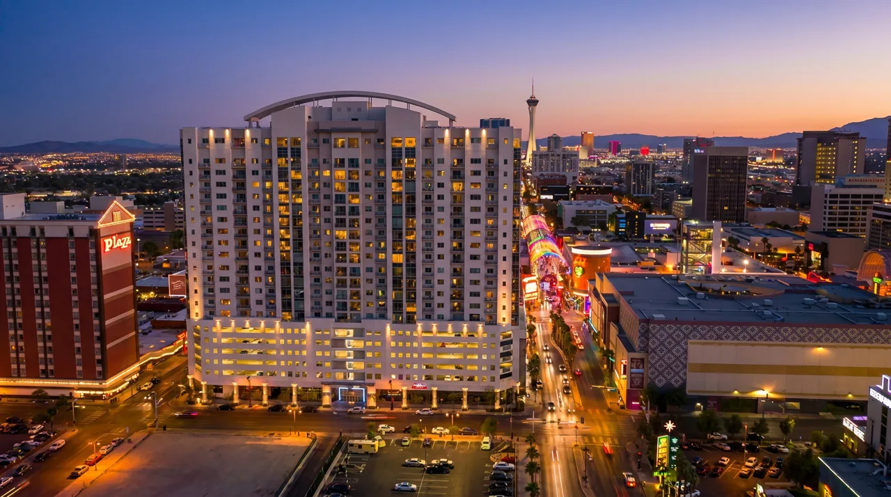 A downtown Las Vegas residential high-rise tower at dusk with Fremont Street and city lights visible below