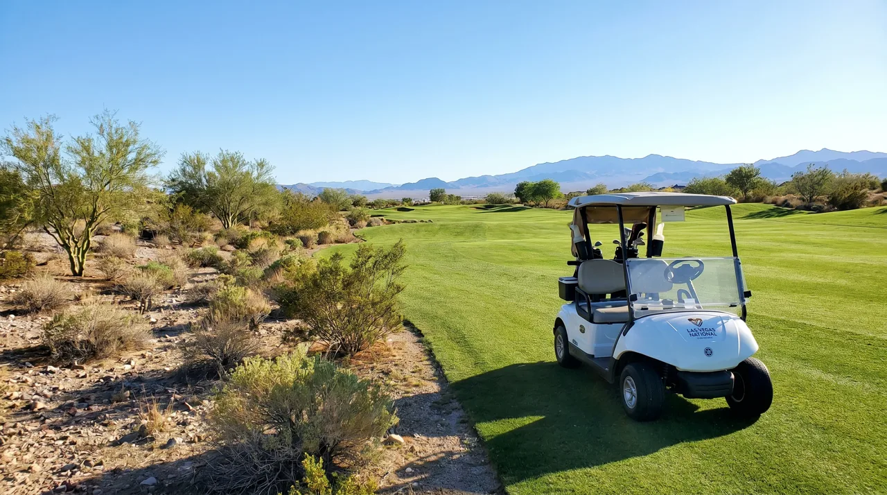 White golf cart parked beside a fairway on a Las Vegas desert golf course