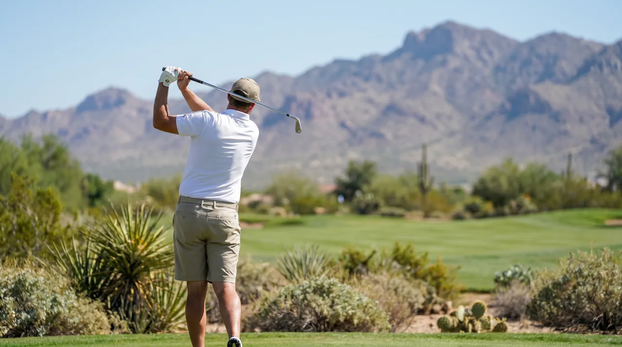 Golfer in mid-swing on a Las Vegas desert golf course under bright sunlight