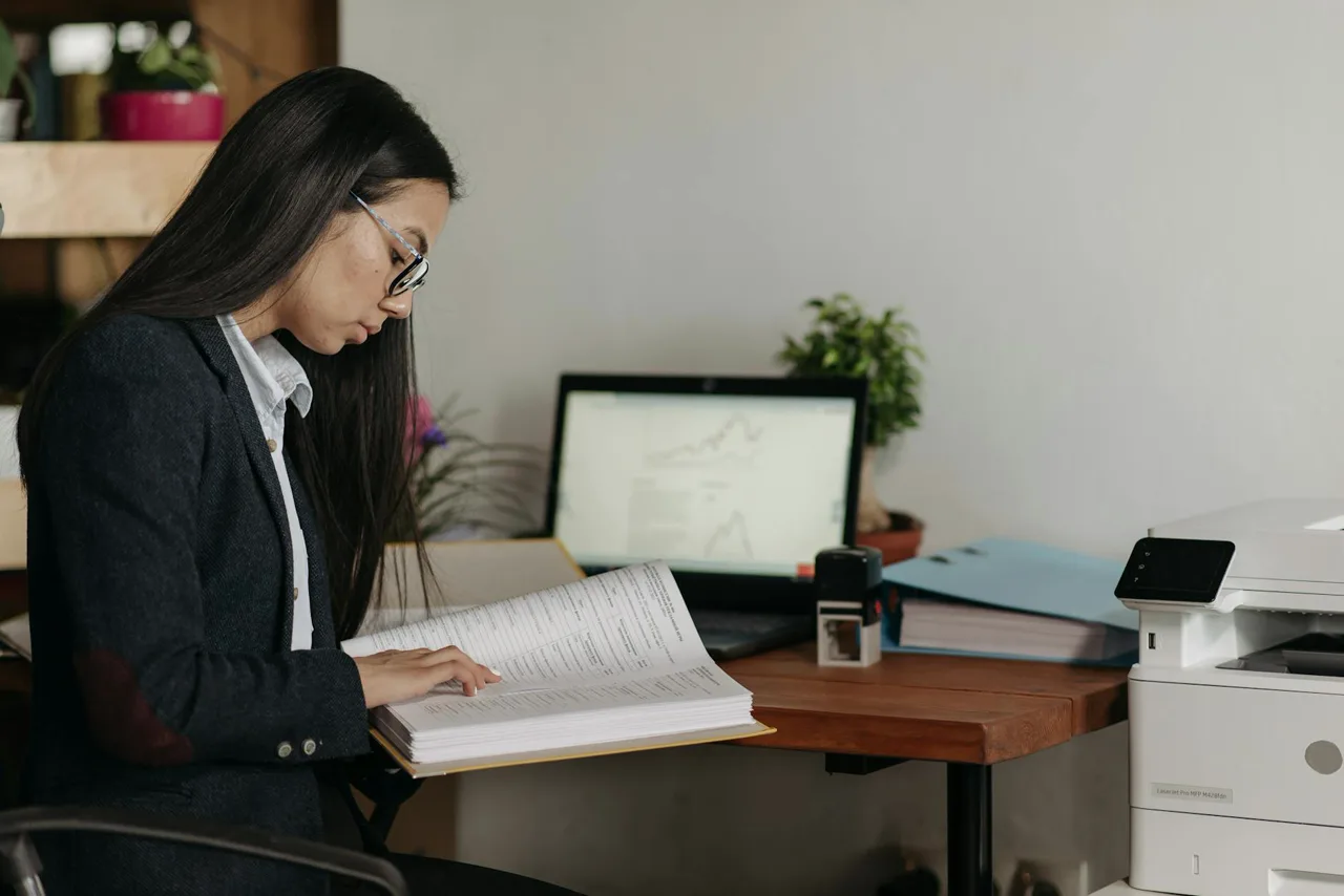 Homebuyer at a desk with reading glasses reviewing a stack of HOA disclosure documents