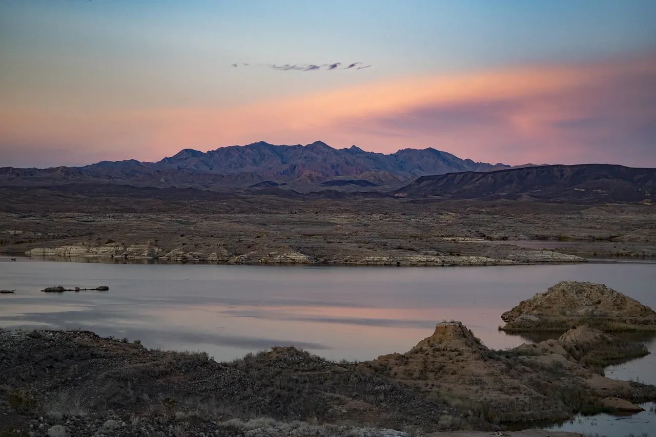 Lake Mead at sunset with red rock cliffs reflecting in the calm water
