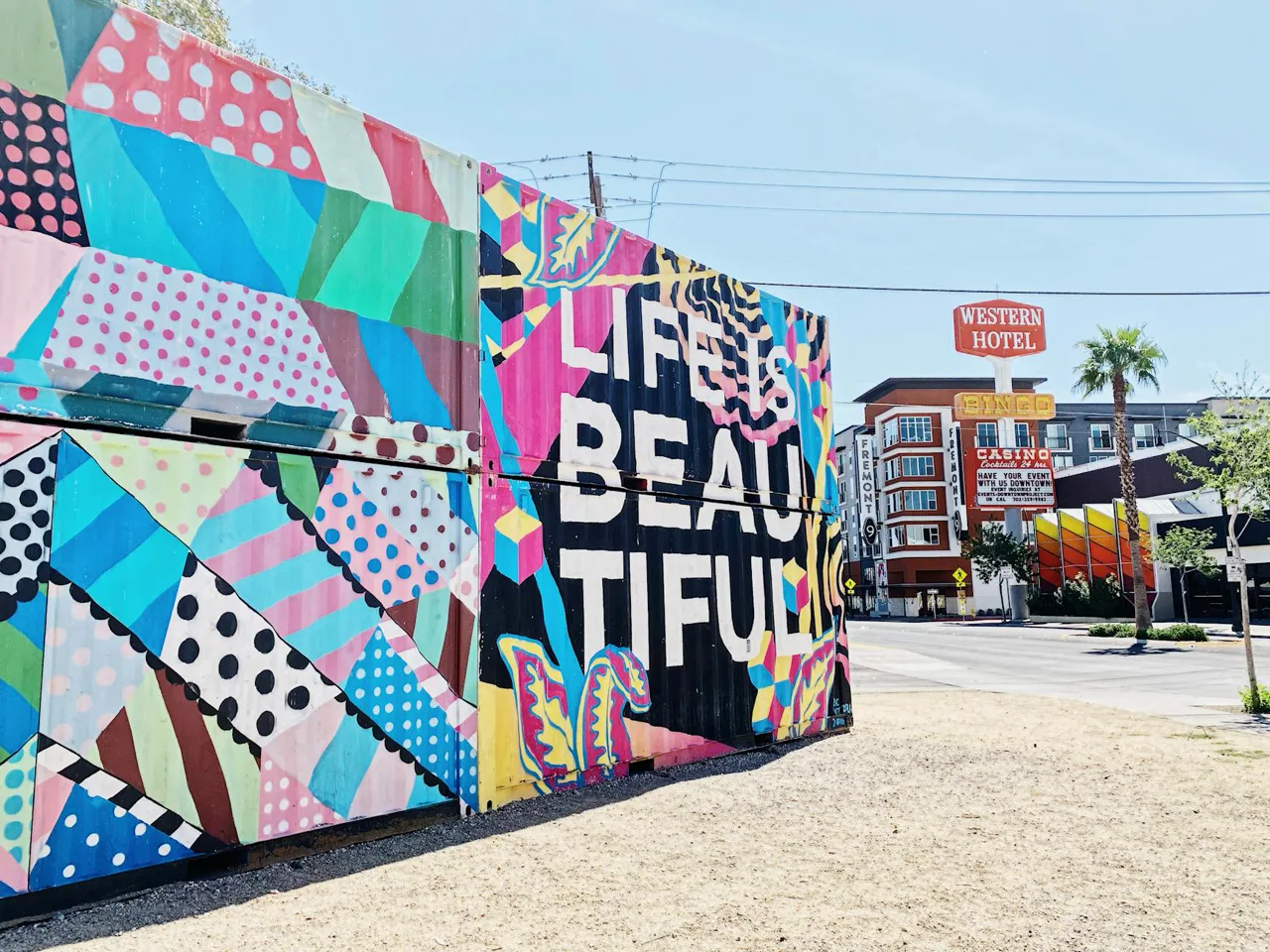 Colorful murals on building walls in the Las Vegas Arts District with small business storefronts along the street
