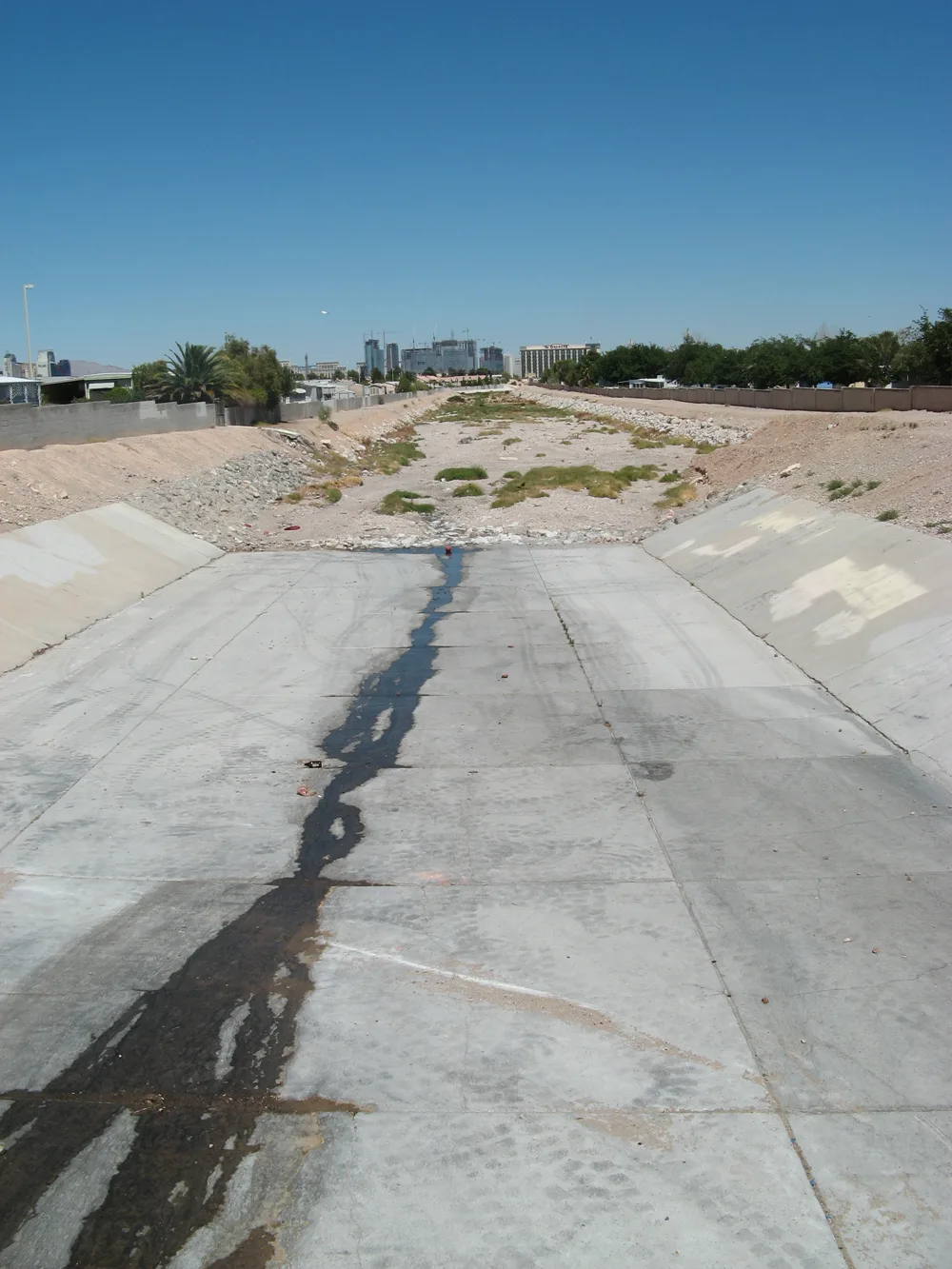 Muddy flash flood water rushing through a concrete flood control channel in Las Vegas