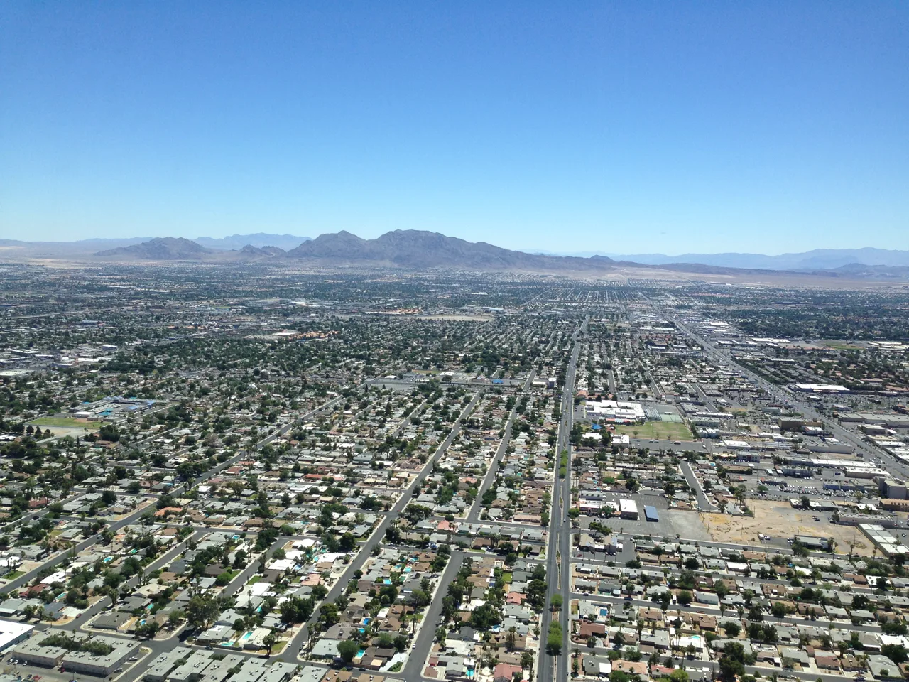 Aerial view of a Las Vegas residential neighborhood with red tile roofs and the Strip skyline in the distance