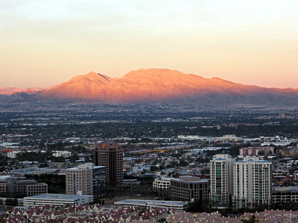 Las Vegas valley at dusk with mountains in the background and residential rooftops in the foreground