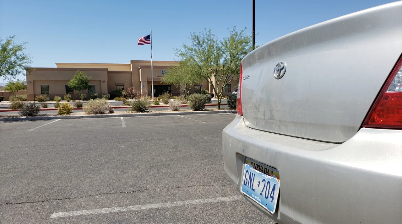 Nevada license plate on the rear of a sedan parked outside a Las Vegas DMV office