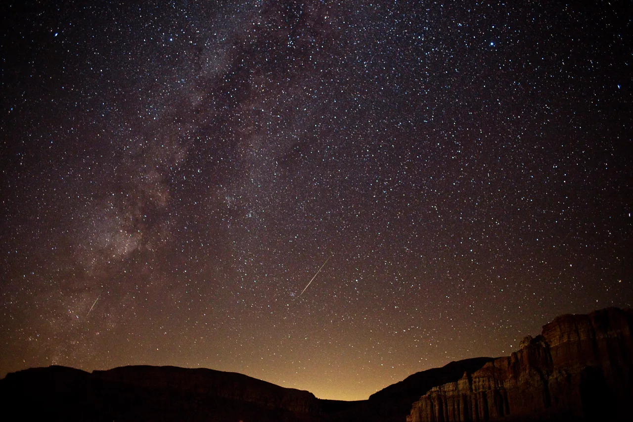 Night sky full of stars over Red Rock Canyon with the Las Vegas valley glow on the horizon