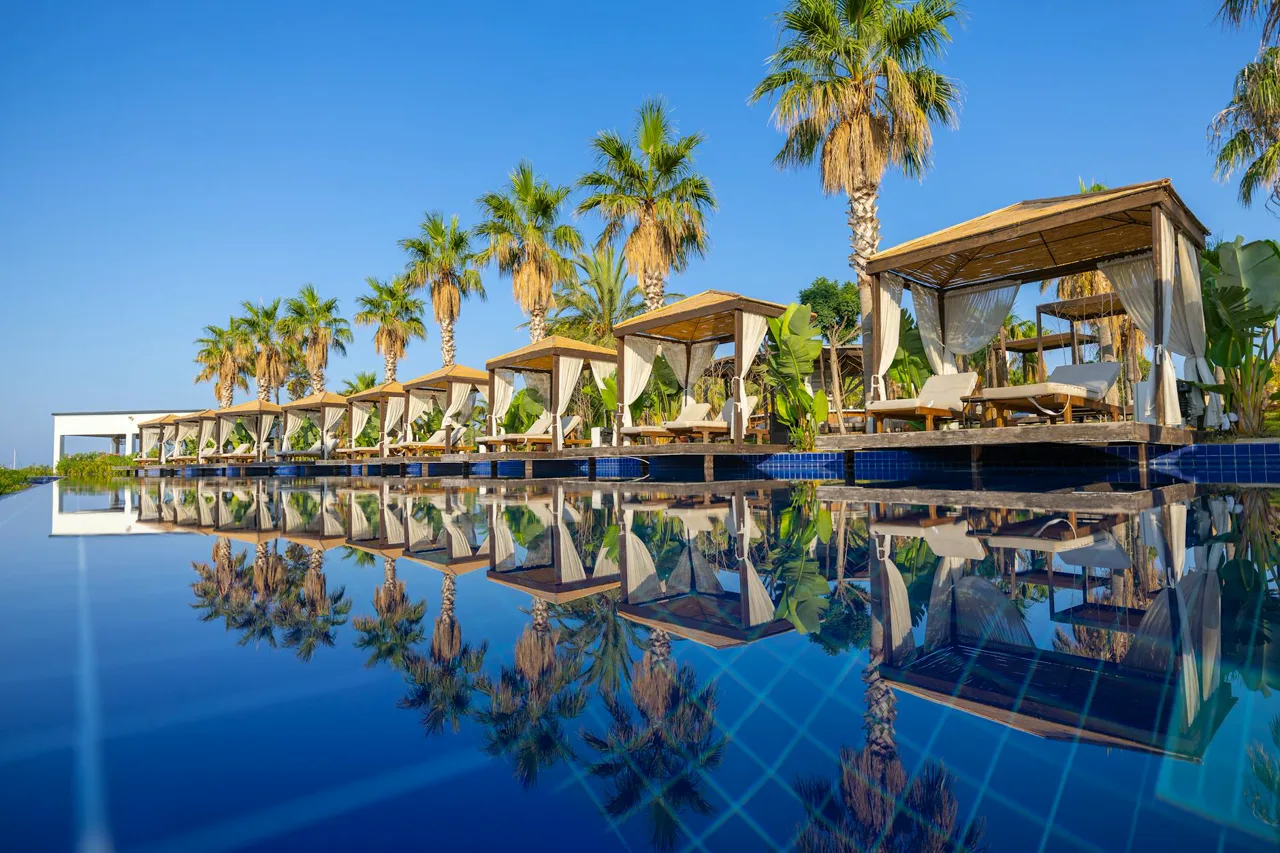 Resort-style swimming pool with cabanas and palm trees at a luxury country club
