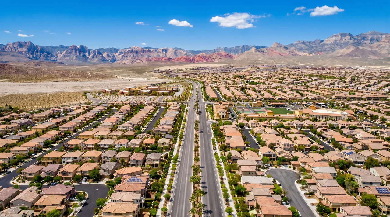 Aerial view of Summerlin master-planned community with red-tile-roofed homes and Red Rock Canyon in the background