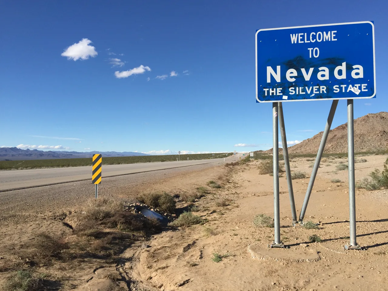 Welcome to Nevada state border sign with desert landscape and blue sky